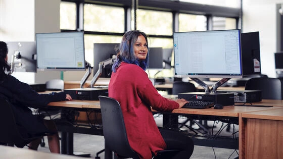 A Deakin postgraduate information technology student works at a desktop computer