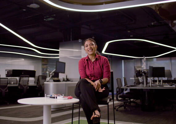 Saloni is sitting on a stool in a Deakin IT lab, speaking to a camera.