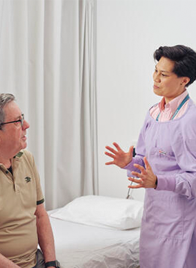 A doctor consults with a patient inside a hospital room.