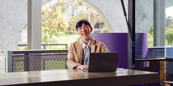 A Deakin international student smiles while studying on an open laptop
