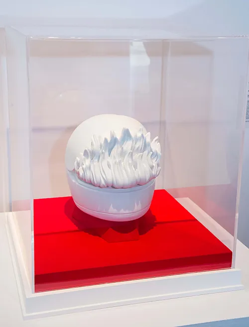 Sculpture of tiny white helmet with flames coming out the visor