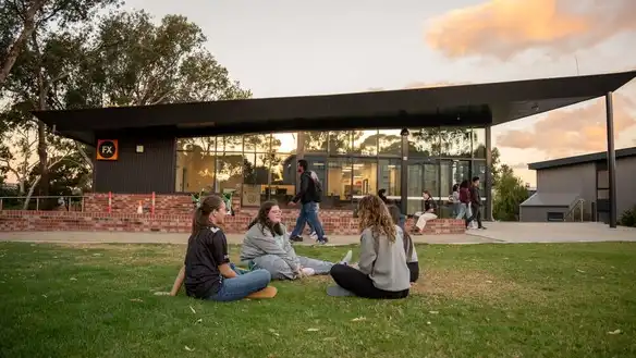 Students sitting on the grass outside student accommodation.