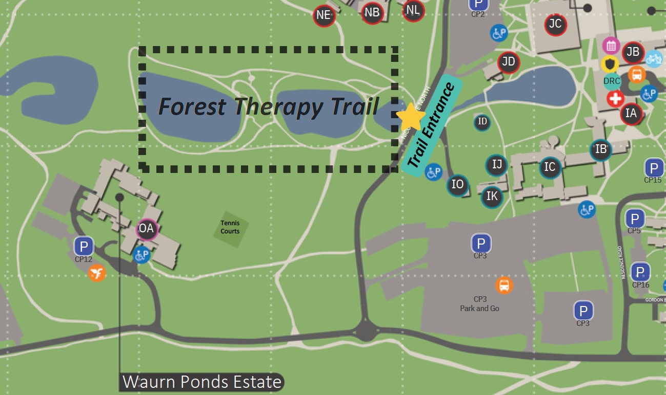 Map showing the location of the Forest Therapy Trail, highlighted by a dashed box and yellow arrow pointing to the trail entrance near buildings, ponds, and parking areas.
