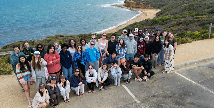 International Summer School students posing for a group photo overlooking the Great Ocean Road coastline.