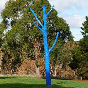 large painted blue tree surrounded by greenery