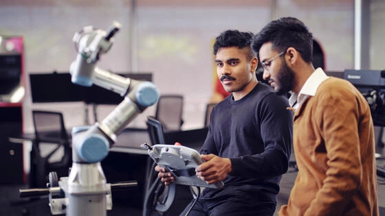 Two Deakin Graduate Certificate of Artificial Intelligence students use a robot. 