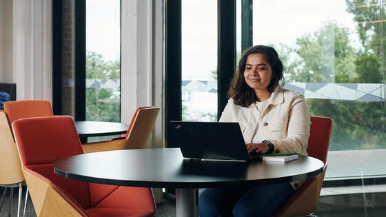 A Deakin postgraduate education research student works on a laptop in the library.