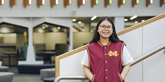 Deakin international student standing and smiling on campus.