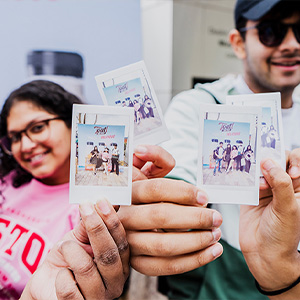 smiling young adults holding up polaroid pictures