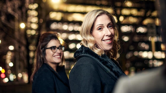 Two Deakin business students outside a city building at night.