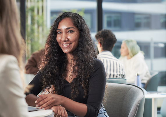 Deakin student sitting at table and smiling on campus.