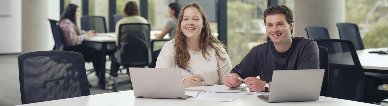 Two Deakin students with laptops studying on the Melbourne Burwood Campus.