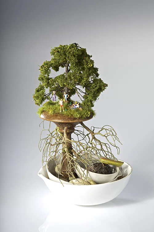 Sculpture of white bowls holding a boat and tree with figurines of people