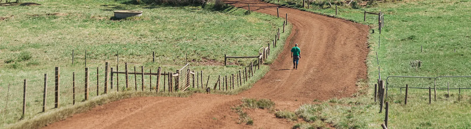 A Graduate Certificate of Agricultural Health and Medicine students walks along a dirt road at a farm. 