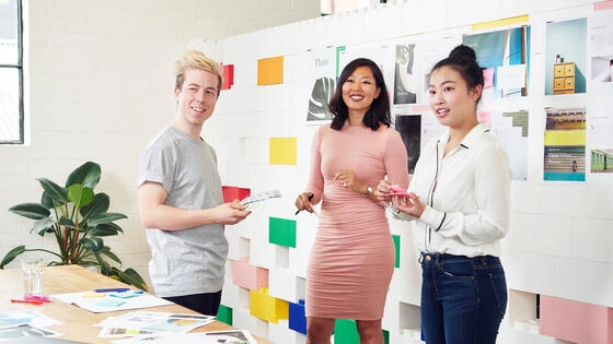 Three postgraduate communication students stand talking.