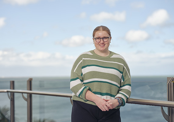 Eloise standing on a balcony with the ocean behind her