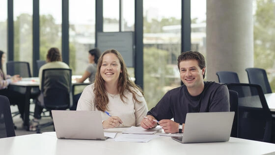 Two Deakin students with laptops studying on the Melbourne Burwood Campus.