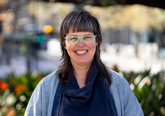 Dr Louisa Smith standing in a park smiling at the viewer.