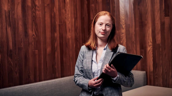 A Deakin postgraduate property student stands holding a binder.